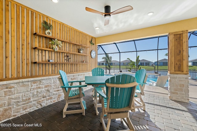 view of patio / terrace featuring a ceiling fan, a lanai, fence, outdoor dining area, and a pool