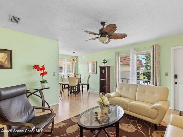 tiled living area with a textured ceiling, ceiling fan, visible vents, and baseboards