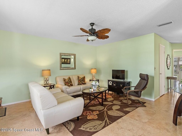 living area featuring a textured ceiling, a ceiling fan, visible vents, baseboards, and tile patterned floors