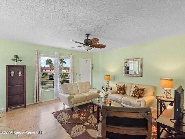 tiled living room with a textured ceiling, baseboards, and a ceiling fan