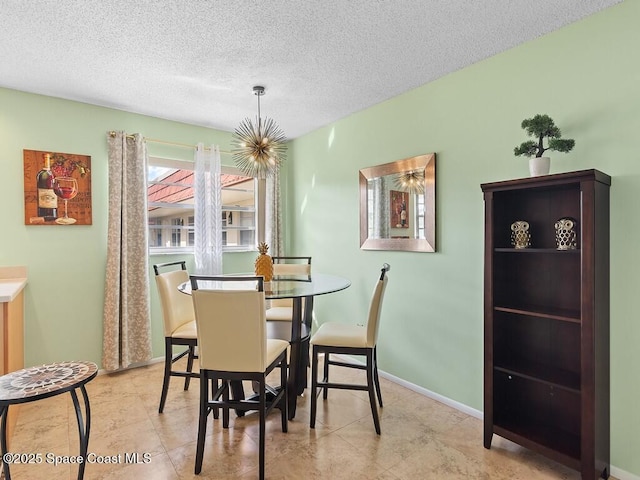 dining room with a textured ceiling, tile patterned flooring, and baseboards