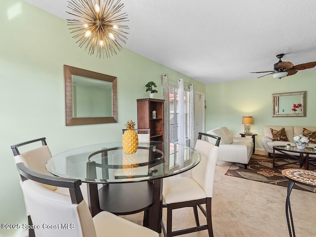 tiled dining area featuring a textured ceiling and ceiling fan with notable chandelier