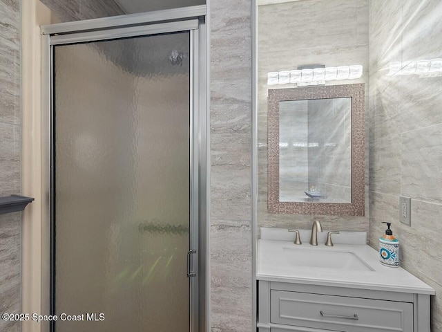 full bath featuring vanity, a shower stall, and tile walls