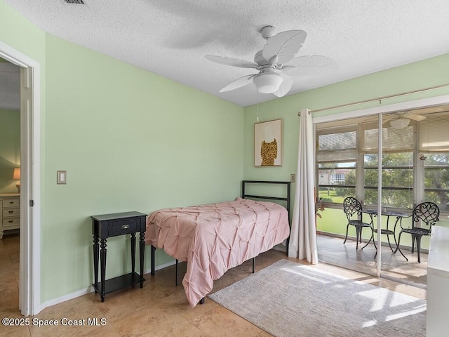 tiled bedroom with a textured ceiling, ceiling fan, and baseboards