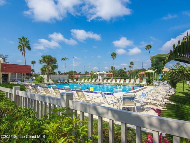 community pool with a patio area and fence