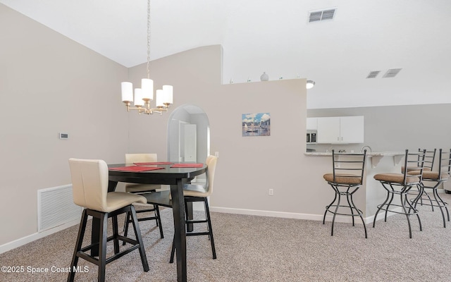 dining room with light colored carpet, visible vents, vaulted ceiling, and baseboards