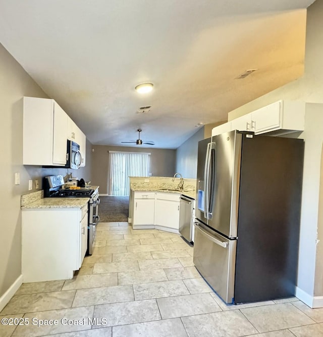 kitchen with ceiling fan, appliances with stainless steel finishes, a peninsula, white cabinetry, and a sink