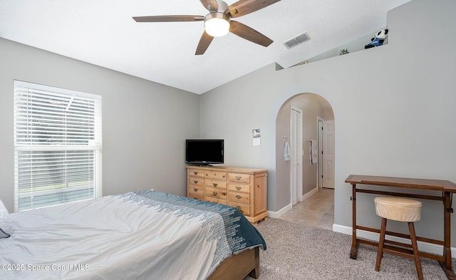 bedroom featuring arched walkways, lofted ceiling, light colored carpet, visible vents, and baseboards