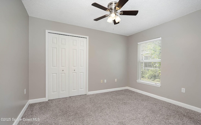 unfurnished bedroom with a textured ceiling, a closet, baseboards, and carpet flooring