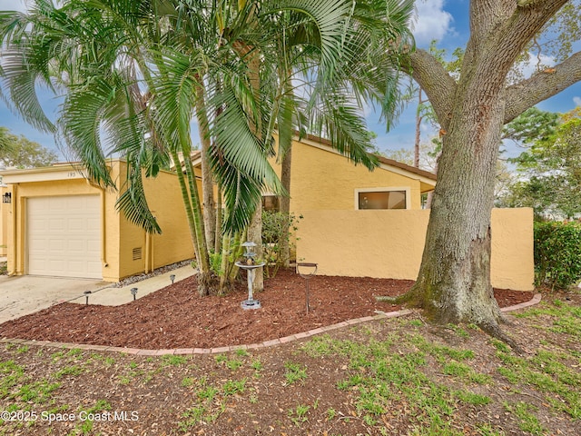 view of side of property with a garage, concrete driveway, and stucco siding