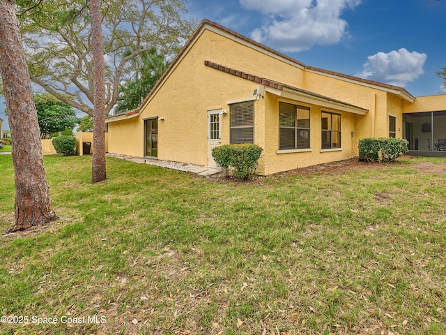 view of side of property featuring a lawn and stucco siding