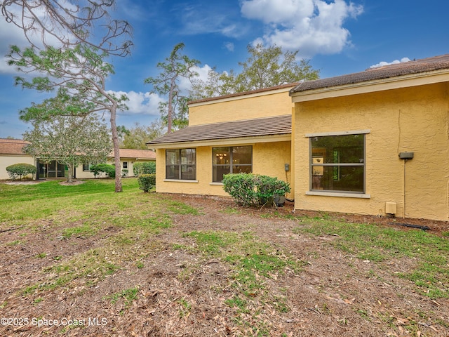 rear view of property with a yard and stucco siding