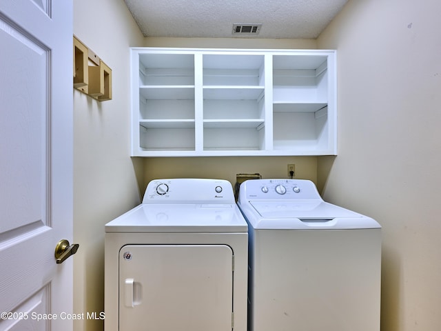 washroom featuring a textured ceiling, laundry area, independent washer and dryer, and visible vents