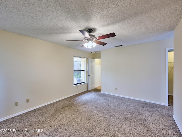 empty room with carpet floors, visible vents, ceiling fan, a textured ceiling, and baseboards