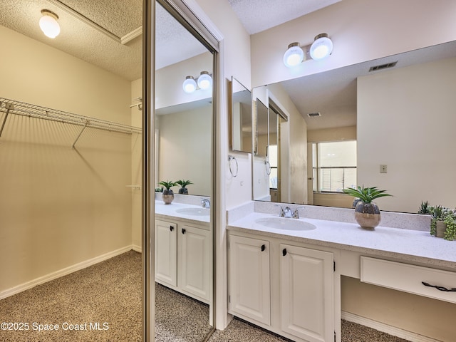 full bathroom featuring a textured ceiling, visible vents, vanity, baseboards, and a spacious closet