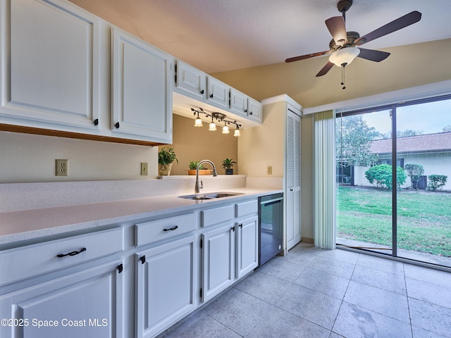 kitchen with a sink, white cabinets, light countertops, and stainless steel dishwasher