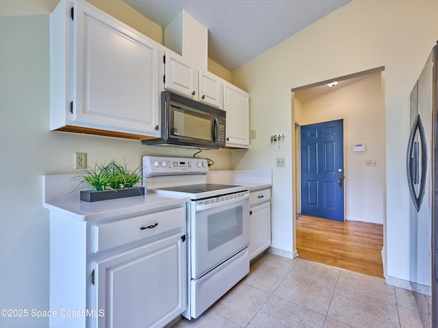 kitchen featuring electric stove, light tile patterned floors, light countertops, black microwave, and stainless steel refrigerator