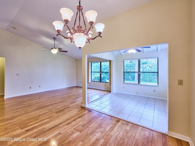 unfurnished room featuring baseboards, vaulted ceiling, light wood finished floors, and ceiling fan with notable chandelier