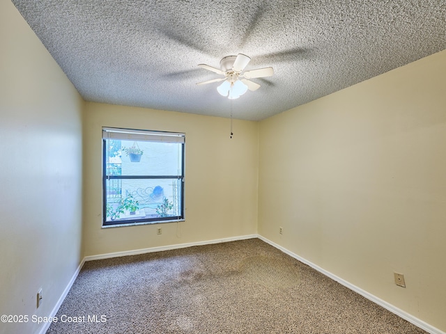 carpeted spare room with a textured ceiling, a ceiling fan, and baseboards