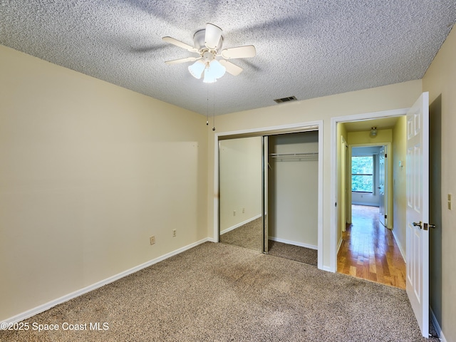 unfurnished bedroom featuring a textured ceiling, a closet, carpet, and baseboards