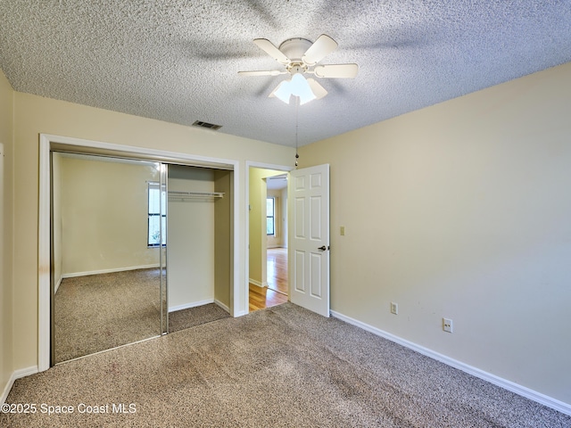 unfurnished bedroom with a textured ceiling, carpet flooring, visible vents, baseboards, and a closet