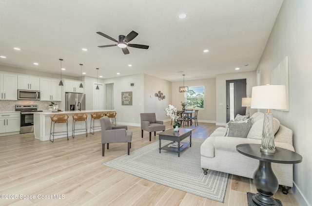 living room with light wood finished floors, ceiling fan, and recessed lighting