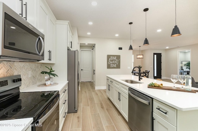 kitchen featuring decorative backsplash, wood tiled floor, stainless steel appliances, white cabinetry, and a sink