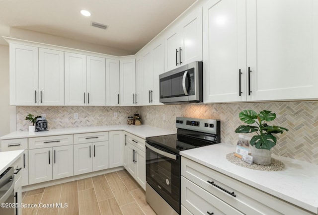 kitchen with appliances with stainless steel finishes, visible vents, and white cabinetry