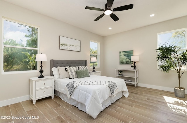 bedroom featuring multiple windows, baseboards, and wood finish floors