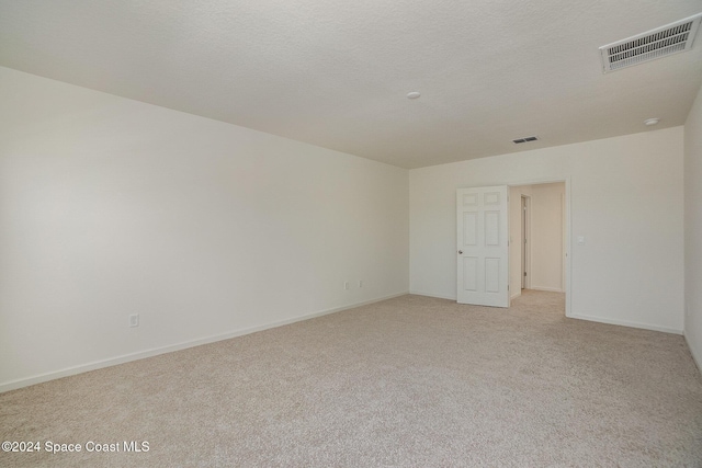 empty room with light colored carpet, visible vents, a textured ceiling, and baseboards