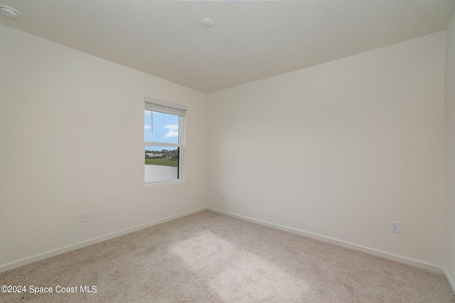 empty room featuring carpet and baseboards