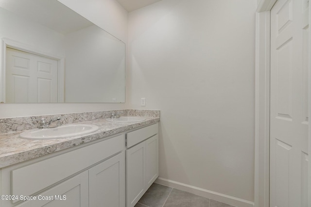 bathroom with double vanity, a sink, baseboards, and tile patterned floors