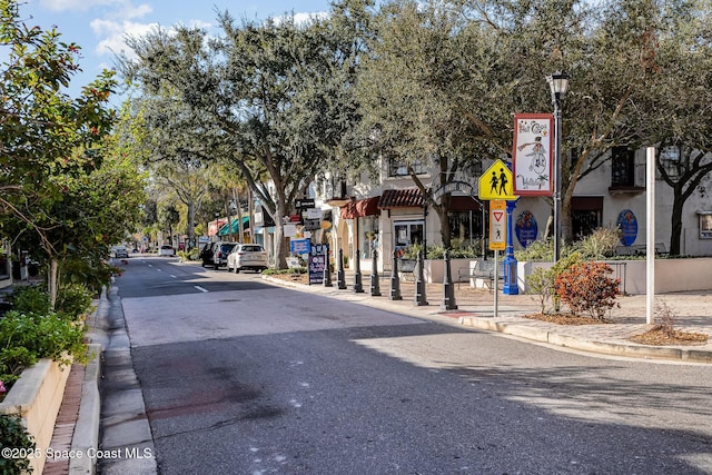 view of street featuring street lights, curbs, traffic signs, and sidewalks