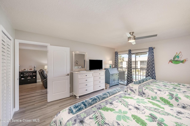 bedroom with light wood-style floors, access to outside, ceiling fan, and a textured ceiling