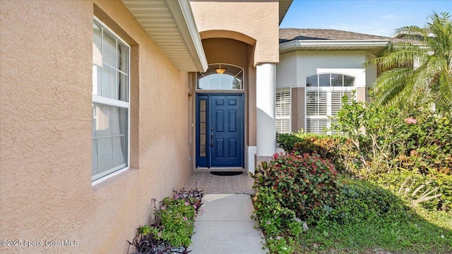 property entrance with a shingled roof and stucco siding