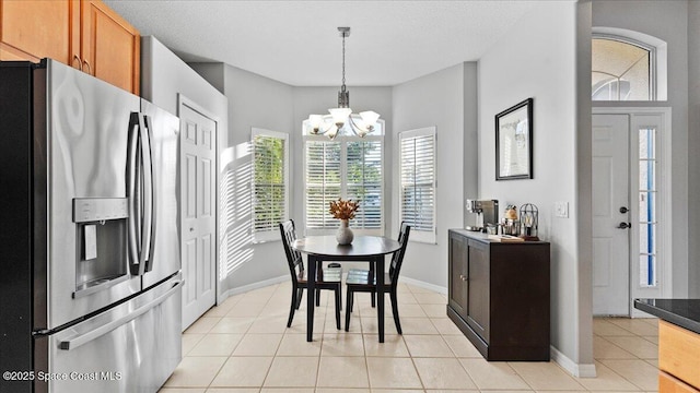 dining space with light tile patterned floors, a textured ceiling, a chandelier, and baseboards