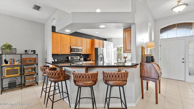 kitchen with a breakfast bar area, visible vents, appliances with stainless steel finishes, a wealth of natural light, and dark countertops