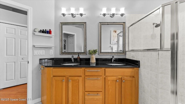 full bath with double vanity, a stall shower, and a sink