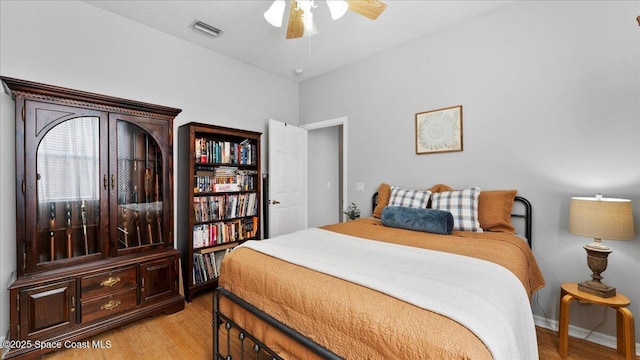 bedroom with light wood finished floors, baseboards, visible vents, and ceiling fan