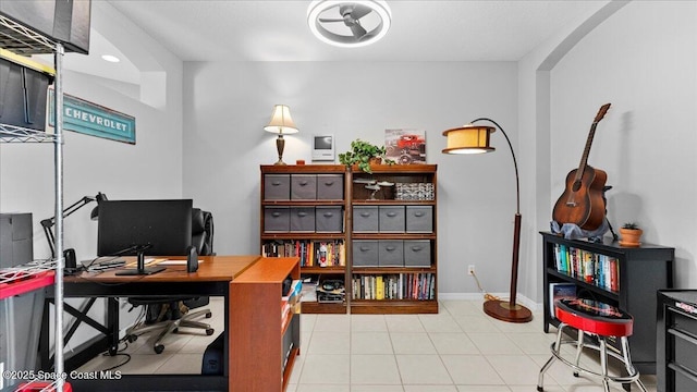 tiled home office featuring arched walkways and baseboards