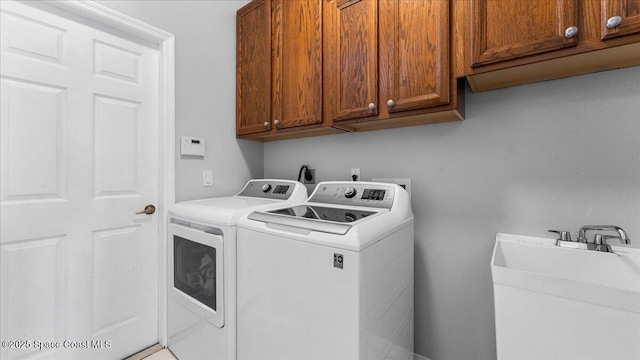 laundry area featuring washer and clothes dryer, a sink, and cabinet space