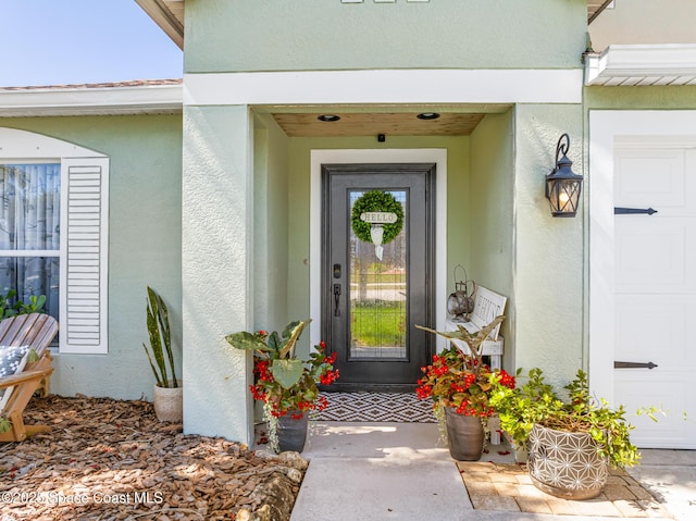 doorway to property with stucco siding and a garage