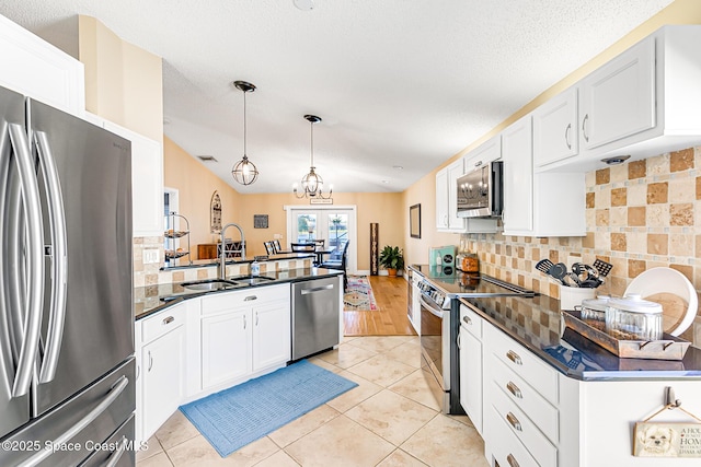 kitchen with a sink, dark countertops, light tile patterned floors, and stainless steel appliances