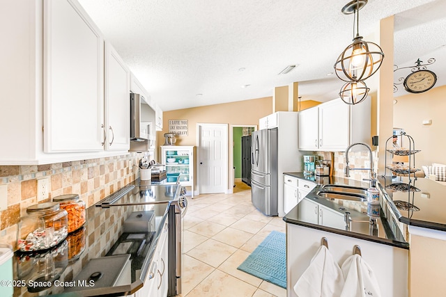 kitchen featuring dark countertops, white cabinets, appliances with stainless steel finishes, and a sink