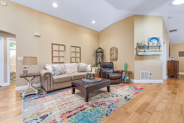 living room with vaulted ceiling, wood finished floors, arched walkways, and visible vents