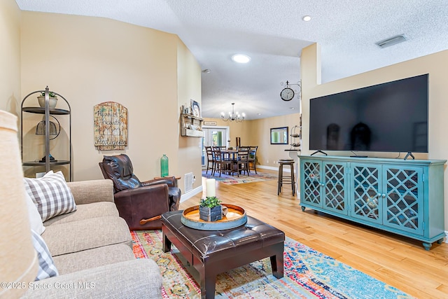 living room featuring visible vents, baseboards, a textured ceiling, and wood finished floors