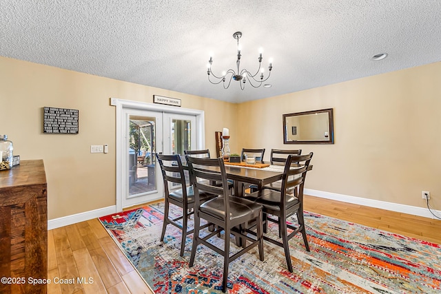 dining space with light wood-style flooring, french doors, a textured ceiling, and baseboards