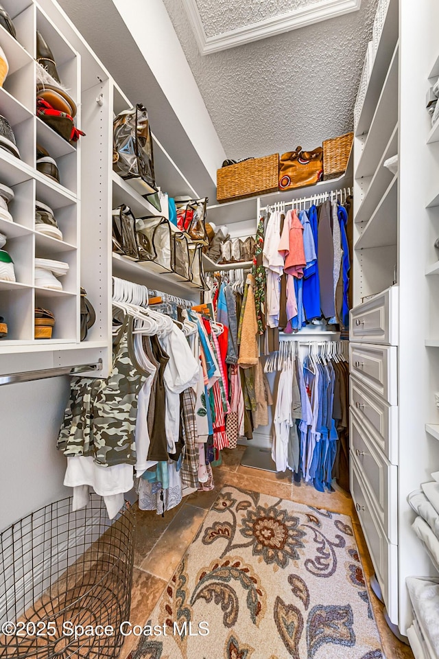 walk in closet featuring stone finish flooring