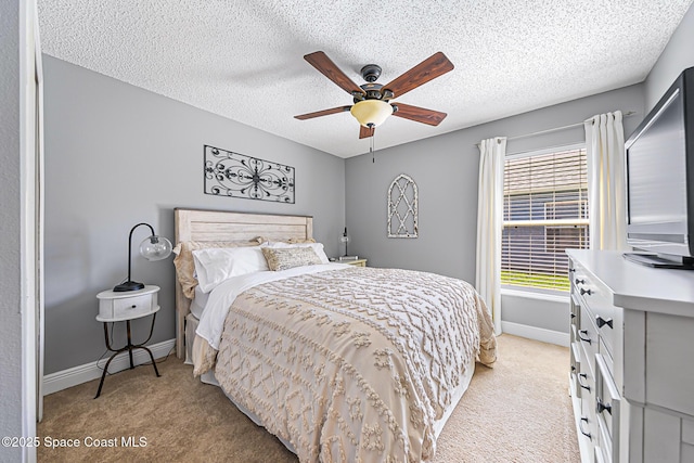 bedroom featuring light colored carpet, a textured ceiling, baseboards, and a ceiling fan