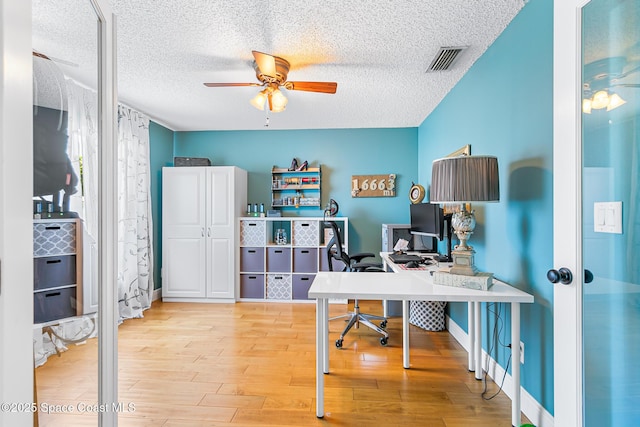 office space with visible vents, baseboards, wood finished floors, a textured ceiling, and a ceiling fan